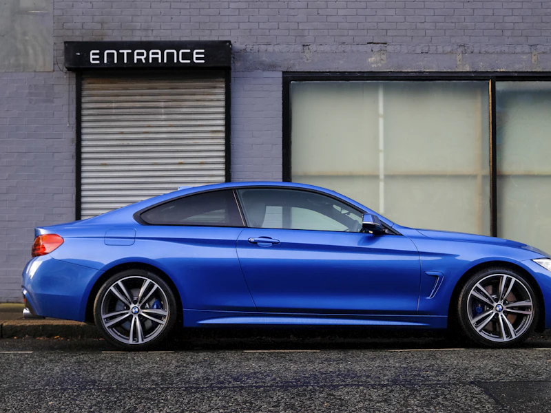 Blaues Coupé vor einer hellen Wand