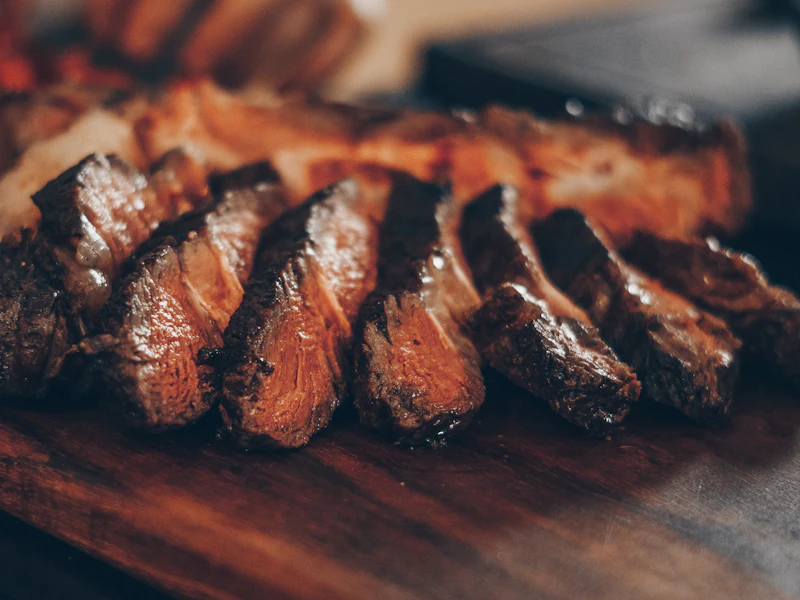 Tranchiertes Steak in Scheiben auf einem Holzbrett.