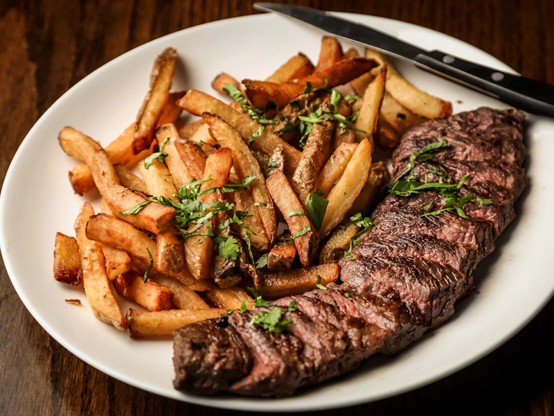 Angerichteter Teller mit Steak und Pommes, Messer am Tellerrand.